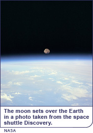 The moon sets over the Earth in a photo taken from the space shuttle Discovery.